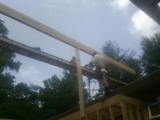Carpenter setting a ridge beam over a new addition frame — Ice Dam Removal by Roofing Brothers in Minco