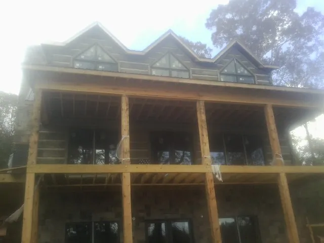 Dormers and porch framing on a large log home under construction — Roof Coating work by our crew in Minco