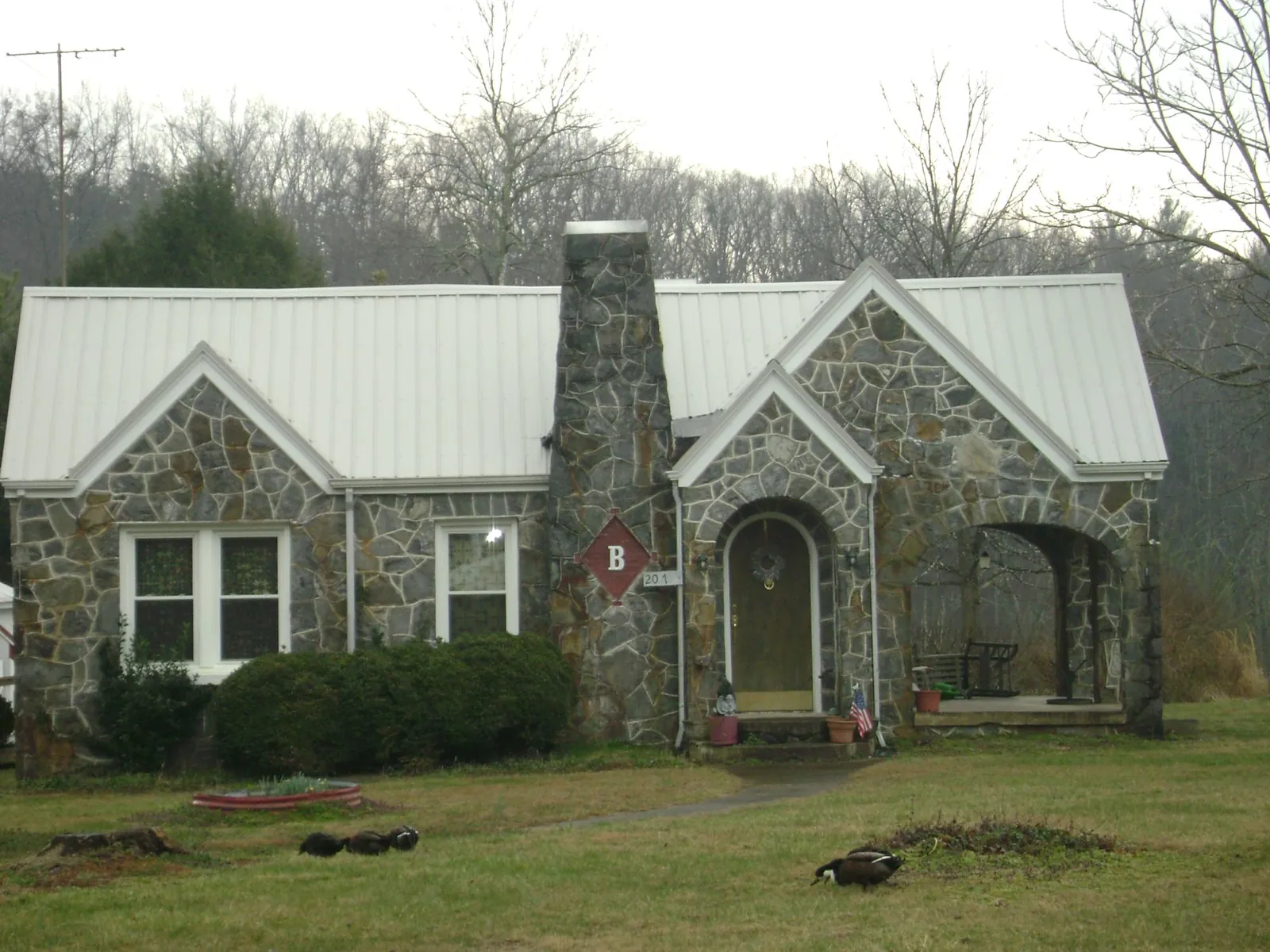 White metal roof on a stone cottage with steep gables in Minco