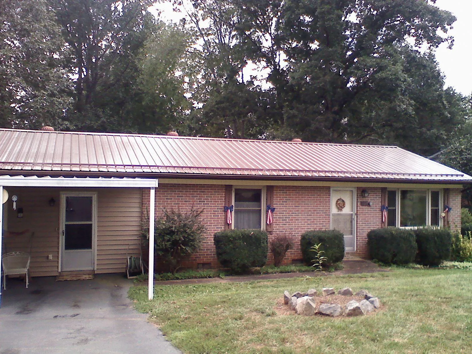 Bronze metal roof and carport on a brick ranch home — Roof Repair work by our crew in Minco