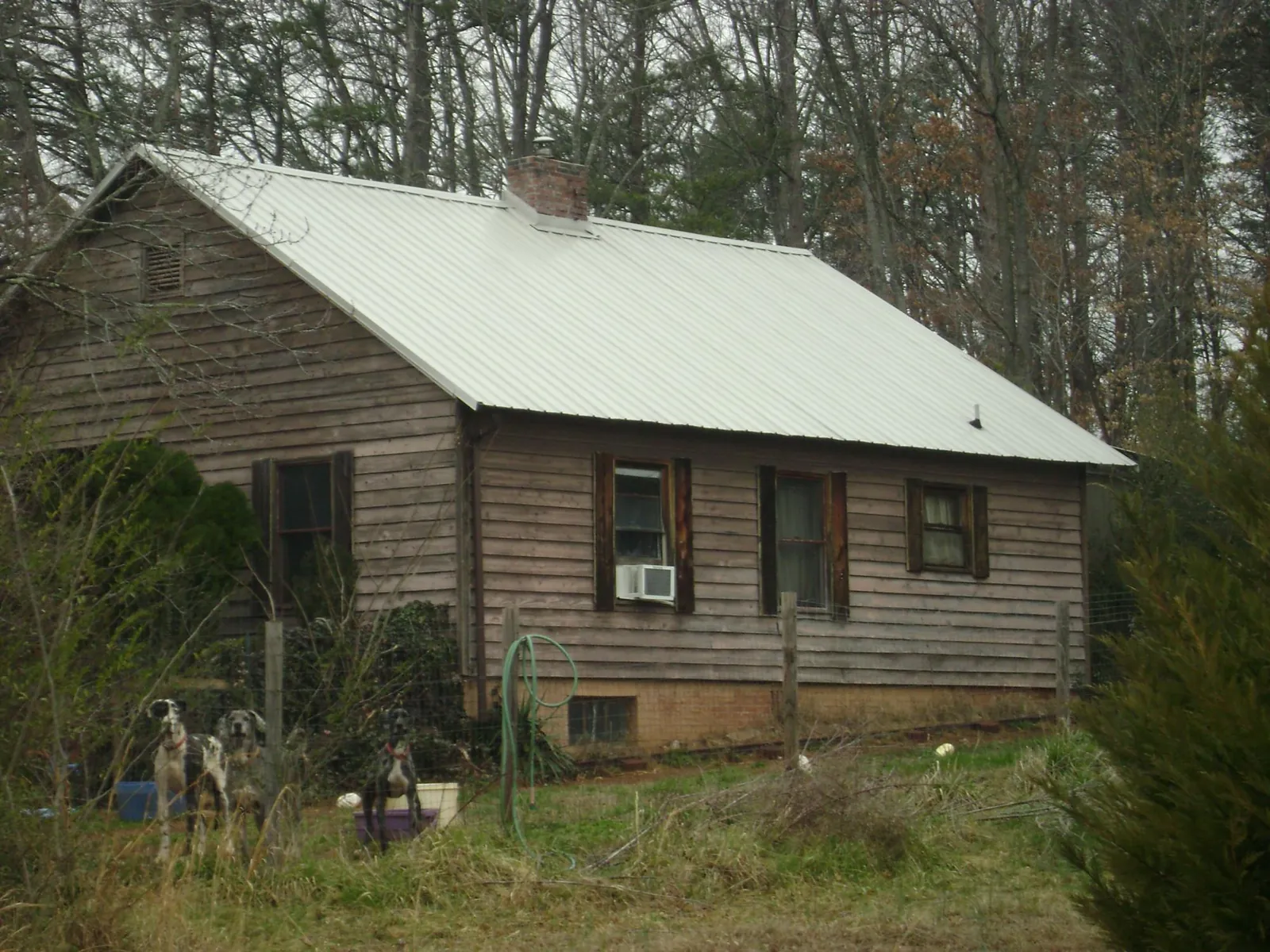 White metal roof on an old wood sided farmhouse, from a Metal Roof Installation job in Minco
